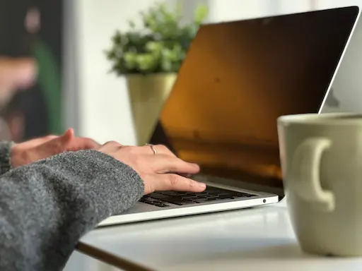 manos de una mujer sobre el teclado de su laptop, trabajando en la actualización de su sitio web.